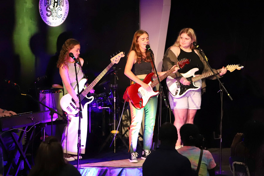 Upper School band members with guitars perform on stage